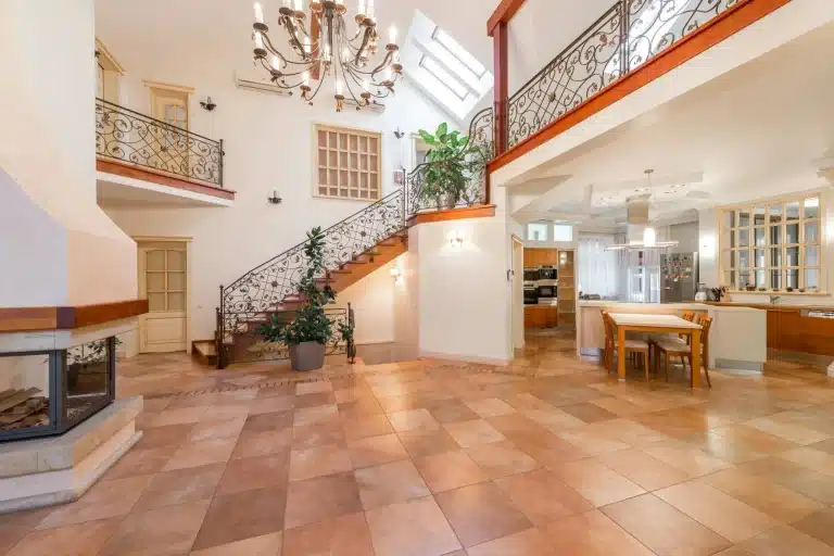Spacious open-plan villa kitchen with terracotta floor, wrought iron staircase, fireplace and double-height skylight.